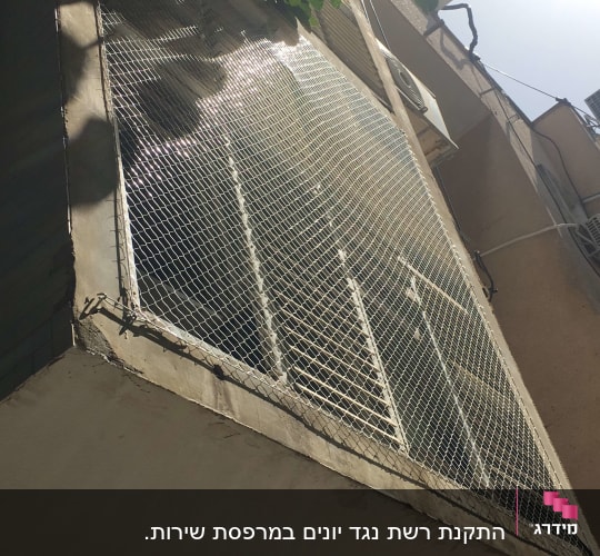 רשת מתכת מותקנת על חלון למניעת כניסת יונים